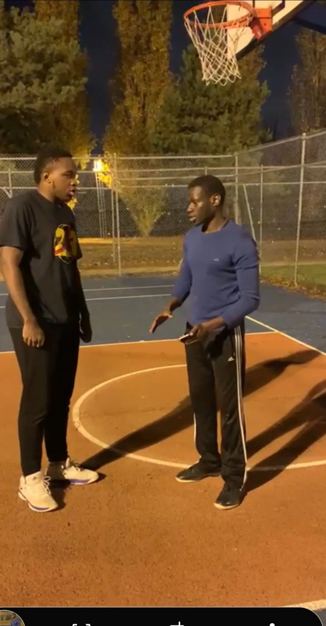 Alassane sur un terrain de basket en soirée, en plein coaching